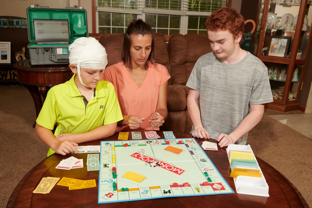 a family playing a board game with a boy getting an EEG